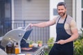 Handsome 40s man preparing barbecue. Male cook cooking meat on barbecue grill. Guy cooking meat on barbecue for summer Royalty Free Stock Photo