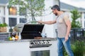 Handsome 40s man preparing barbecue. Male cook cooking meat on barbecue grill. Guy cooking meat on barbecue for summer Royalty Free Stock Photo