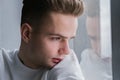 handsome, sad lonely teenager, young guy looks out the window