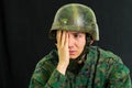 Handsome sad young soldier wearing uniform suffering from stress with his hand covering his face, in a black background Royalty Free Stock Photo