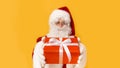 Handsome Santa giving present in red box to you on orange