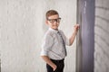 Handsome school boy in googles white shirt tie standing close to school desk with numbers above around the head. Royalty Free Stock Photo