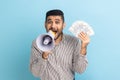 Handsome screaming in megaphone businessman with beard holding fan of dollars, announcing bonus.