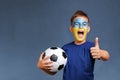 Handsome screaming Ukrainian fanboy holds soccer ball and gesturing thumbs up Royalty Free Stock Photo