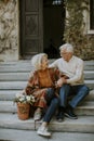 Senior couple sitting on stairs with basket full of flowers and groceries Royalty Free Stock Photo