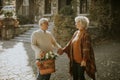 Senior couple walking with basket full of flowers and groceries in autumn park Royalty Free Stock Photo