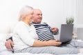 Handsome senior couple woman and man sitting in bed using laptop at home Royalty Free Stock Photo
