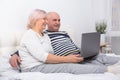 Handsome senior couple woman and man sitting in bed using laptop at home Royalty Free Stock Photo