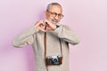 Handsome senior man with beard holding vintage camera smiling in love doing heart symbol shape with hands Royalty Free Stock Photo