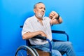 Handsome senior man with beard sitting on wheelchair looking unhappy and angry showing rejection and negative with thumbs down Royalty Free Stock Photo