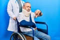 Handsome senior man with beard sitting on wheelchair with neck collar looking unhappy and angry showing rejection and negative Royalty Free Stock Photo