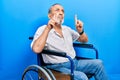 Handsome senior man with beard sitting on wheelchair pointing up looking sad and upset, indicating direction with fingers, unhappy Royalty Free Stock Photo