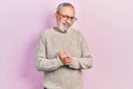 Handsome senior man with beard wearing casual sweater and glasses with hands together and crossed fingers smiling relaxed and Royalty Free Stock Photo