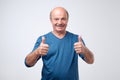 Handsome senior man in blue shirt shows thumb up. Royalty Free Stock Photo