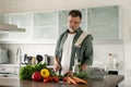 Handsome senior man cooking at home preparing salad in kitchen Royalty Free Stock Photo