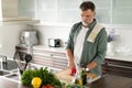 Handsome senior man cooking at home preparing salad in kitchen Royalty Free Stock Photo