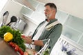 Handsome senior man cooking at home preparing salad in kitchen Royalty Free Stock Photo