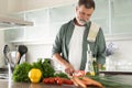 Handsome senior man cooking at home preparing salad in kitchen Royalty Free Stock Photo