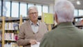 Handsome senior man disputing about book with friend in library