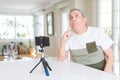 Handsome senior man doing video conference talking to the smartphone camera with hand on chin thinking about question, pensive Royalty Free Stock Photo