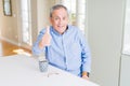 Handsome senior man drinking a cup of coffee at home doing happy thumbs up gesture with hand Royalty Free Stock Photo