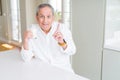 Handsome senior man drinking a glass of fresh milk at breakfast surprised with an idea or question pointing finger with happy Royalty Free Stock Photo