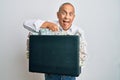 Handsome senior man holding briefcase full of dollars sticking tongue out happy with funny expression Royalty Free Stock Photo