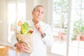 Handsome senior man holding a paper bag of fresh groceries from the supermarket serious face thinking about question, very Royalty Free Stock Photo