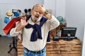 Handsome senior man holding shopping bags at boutique shop smiling and laughing with hand on face covering eyes for surprise