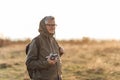 Handsome senior man photographer standing in autumn park and taking pictures with camera Royalty Free Stock Photo