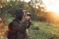 Handsome senior man photographer standing in autumn park and taking pictures with camera Royalty Free Stock Photo