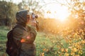 Handsome senior man photographer standing in autumn park and taking pictures with camera Royalty Free Stock Photo