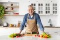 Handsome senior man posing at kitchen interior while cooking healthy food Royalty Free Stock Photo