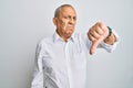 Handsome senior man wearing casual white shirt looking unhappy and angry showing rejection and negative with thumbs down gesture Royalty Free Stock Photo