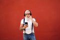 Handsome senior man with white beard, mustache and tattoos listening to music with headphones and mobile phone. Concept of elderly Royalty Free Stock Photo