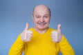 Handsome senior man in yellow sweater shows thumb up. Royalty Free Stock Photo