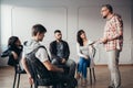 Handsome senior professional therapist stands in front of a group of people of different ages during meeting for people with