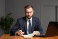 Handsome serious businessman is making notes while working on a laptop Royalty Free Stock Photo