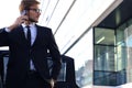 Handsome serious young businessman standing near his comfortable new car and going to the office Royalty Free Stock Photo