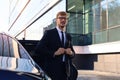 Handsome serious young businessman standing near his comfortable new car and going to the office Royalty Free Stock Photo