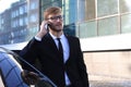 Handsome serious young businessman standing near his comfortable new car and going to the office Royalty Free Stock Photo