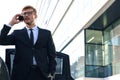 Handsome serious young businessman standing near his comfortable new car and going to the office Royalty Free Stock Photo