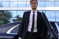 Handsome serious young businessman standing near his comfortable new car and going to the office Royalty Free Stock Photo