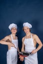 Two handsome chefs with apron on naked muscular body with kitchen utensils on blue background