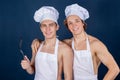 Two handsome chefs with apron on naked muscular body with kitchen utensils on blue background