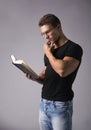 Handsome Muscular Man Reading Big Book on Grey Royalty Free Stock Photo