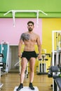 Handsome, sexy, topless, shirtless man standing at gym while looking aside