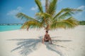 Handsome sexy young man standing sitting in the shade under palm tree at the tropical island Royalty Free Stock Photo