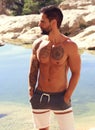 Handsome shirtless fitness man in front of water