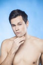 Handsome shirtless man in front of mirror looking at his chin checking is he well-shaved Royalty Free Stock Photo